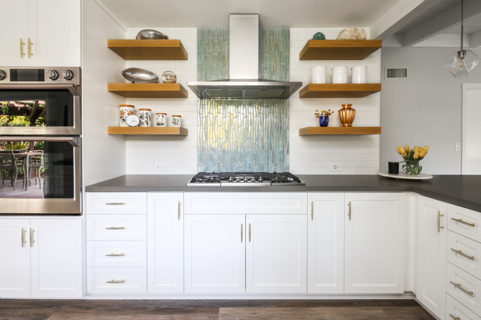 Idéer för ett mellanstort retro grå kök och matrum, med skåp i shakerstil, vita skåp, vitt stänkskydd, stänkskydd i keramik, rostfria vitvaror, mellanmörkt trägolv, en halv köksö och grått golv