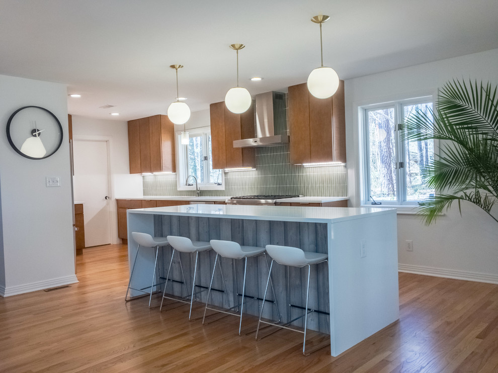 Large 1960s l-shaped medium tone wood floor open concept kitchen photo in Raleigh with an undermount sink, flat-panel cabinets, medium tone wood cabinets, quartz countertops, green backsplash, glass tile backsplash, stainless steel appliances and an island