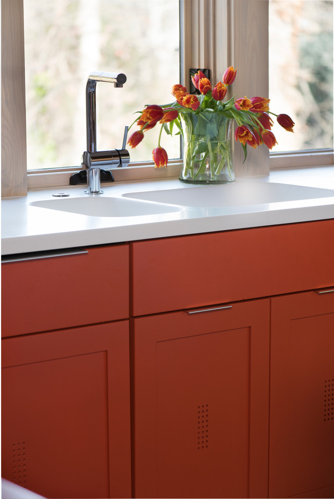 Foto di una cucina minimalista di medie dimensioni con lavello a doppia vasca, ante in stile shaker, ante arancioni, top in superficie solida, elettrodomestici in acciaio inossidabile e parquet chiaro