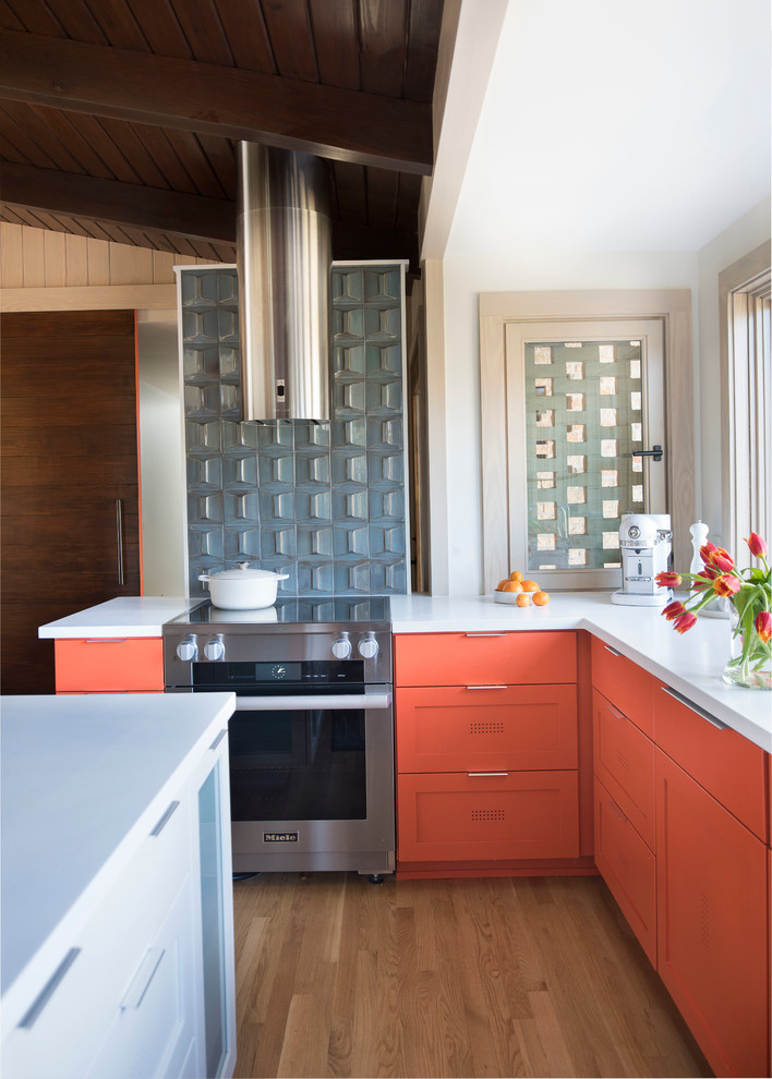 Immagine di una cucina minimalista di medie dimensioni con lavello a doppia vasca, ante in stile shaker, ante arancioni, top in superficie solida, elettrodomestici in acciaio inossidabile e parquet chiaro