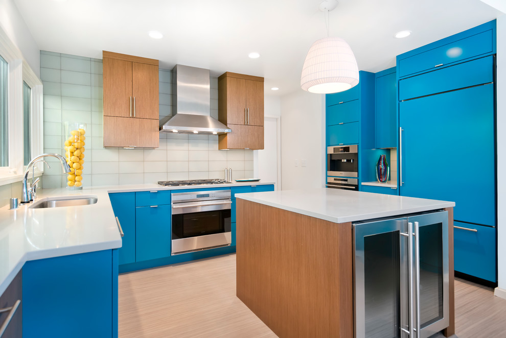 Idéer för ett avskilt modernt u-kök, med en undermonterad diskho, släta luckor, blå skåp, bänkskiva i kvarts, stänkskydd i glaskakel och rostfria vitvaror