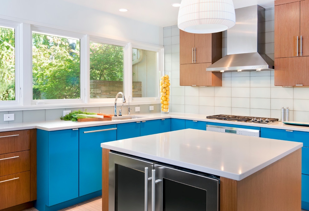 Example of a trendy u-shaped enclosed kitchen design in Milwaukee with an undermount sink, flat-panel cabinets, blue cabinets, quartzite countertops, glass tile backsplash and stainless steel appliances