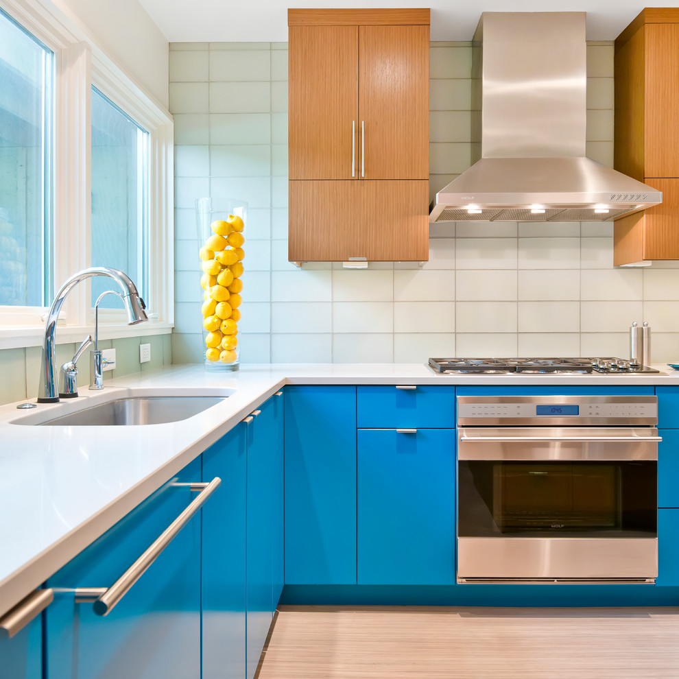 Exempel på ett avskilt modernt u-kök, med en undermonterad diskho, släta luckor, blå skåp, bänkskiva i kvartsit, stänkskydd i glaskakel och rostfria vitvaror