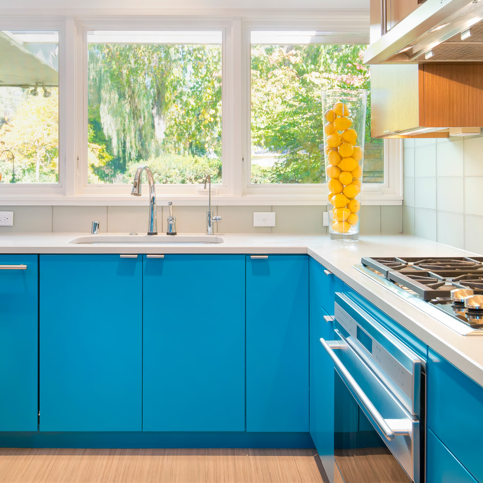Inspiration for a contemporary u-shaped enclosed kitchen remodel in Milwaukee with an undermount sink, flat-panel cabinets, blue cabinets, quartzite countertops, glass tile backsplash and stainless steel appliances