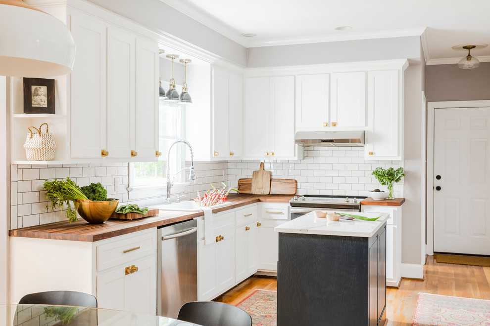 Design ideas for a classic l-shaped kitchen/diner in Richmond with a built-in sink, shaker cabinets, white cabinets, wood worktops, white splashback, metro tiled splashback, stainless steel appliances, medium hardwood flooring, an island, brown floors and brown worktops.