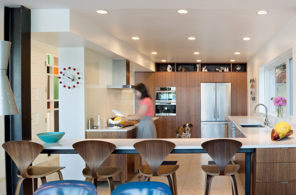 Moderne Küche in U-Form mit flächenbündigen Schrankfronten, Glasrückwand, Küchengeräten aus Edelstahl, dunklen Holzschränken, Unterbauwaschbecken, Granit-Arbeitsplatte, Küchenrückwand in Weiß, Halbinsel, Korkboden und beigem Boden in Seattle