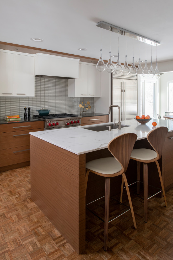 Immagine di una cucina moderna di medie dimensioni con lavello sottopiano, ante lisce, top in quarzo composito, paraspruzzi grigio, elettrodomestici in acciaio inossidabile, parquet chiaro e pavimento marrone