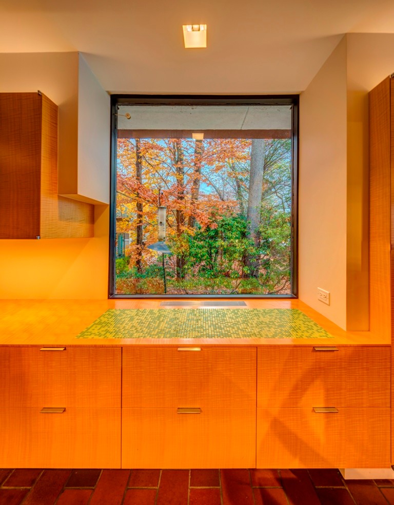 Example of a large trendy galley terra-cotta tile eat-in kitchen design in New York with an integrated sink, flat-panel cabinets, light wood cabinets, concrete countertops, green backsplash, ceramic backsplash, stainless steel appliances and an island