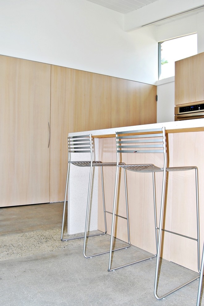 Foto di una cucina moderna di medie dimensioni con lavello sottopiano, ante lisce, ante in legno chiaro, top in quarzo composito, paraspruzzi bianco, elettrodomestici in acciaio inossidabile e pavimento in cemento
