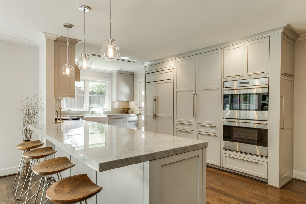 Example of a mid-sized transitional u-shaped medium tone wood floor open concept kitchen design in Dallas with a farmhouse sink, shaker cabinets, gray cabinets, quartzite countertops, gray backsplash, ceramic backsplash, stainless steel appliances and a peninsula