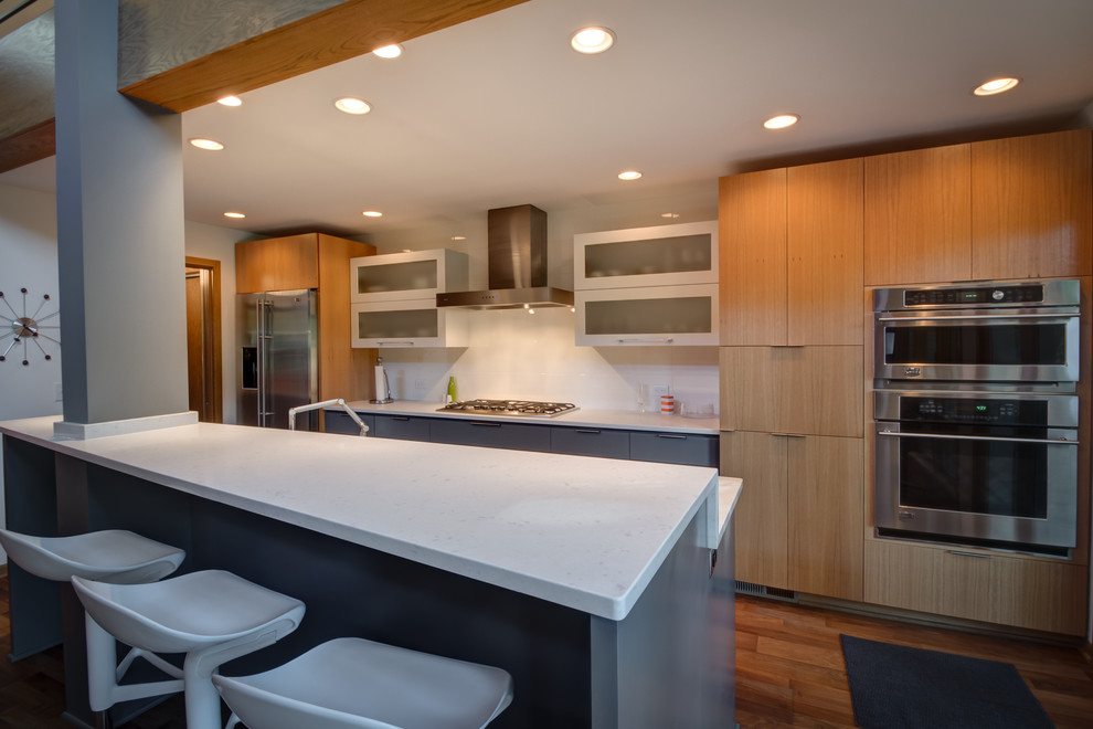 Design ideas for a midcentury galley open plan kitchen in Minneapolis with flat-panel cabinets, grey cabinets, engineered stone countertops, white splashback, stainless steel appliances, medium hardwood flooring and an island.