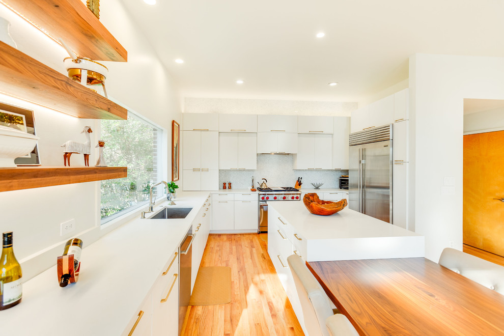 Inspiration for a large modern u-shaped medium tone wood floor eat-in kitchen remodel in Birmingham with an undermount sink, flat-panel cabinets, white cabinets, quartz countertops, white backsplash, porcelain backsplash, stainless steel appliances, an island and white countertops