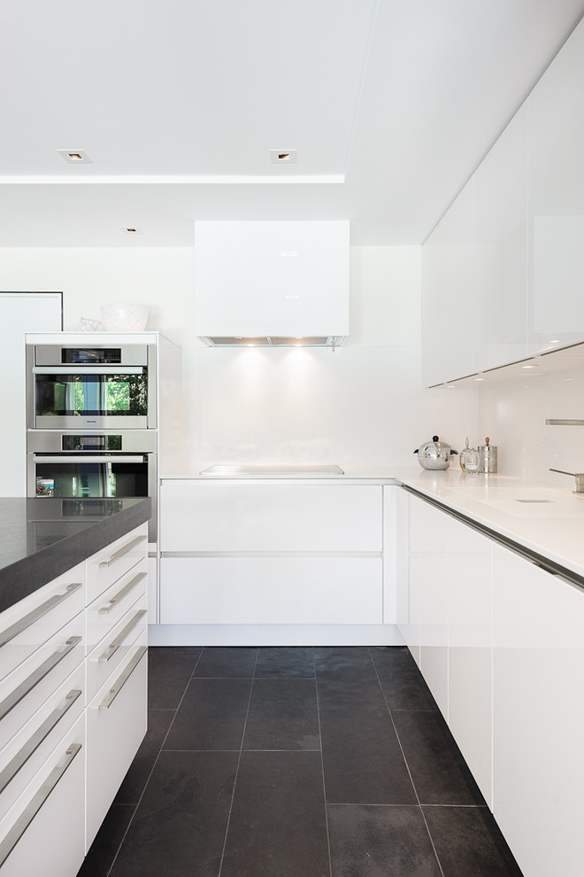 Mid-sized trendy l-shaped black floor and slate floor kitchen photo in Ottawa with flat-panel cabinets, white cabinets, quartzite countertops, white backsplash, stainless steel appliances and an island