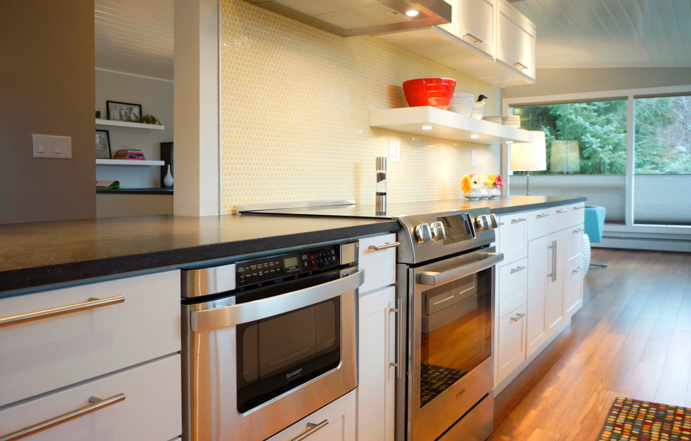 Small 1950s galley bamboo floor open concept kitchen photo in Other with an undermount sink, shaker cabinets, white cabinets, quartz countertops, yellow backsplash, ceramic backsplash, stainless steel appliances and a peninsula