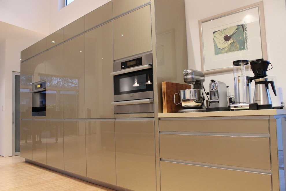 Immagine di una cucina moderna con lavello sottopiano, ante lisce, ante beige, top in quarzo composito, paraspruzzi beige, elettrodomestici da incasso e parquet chiaro