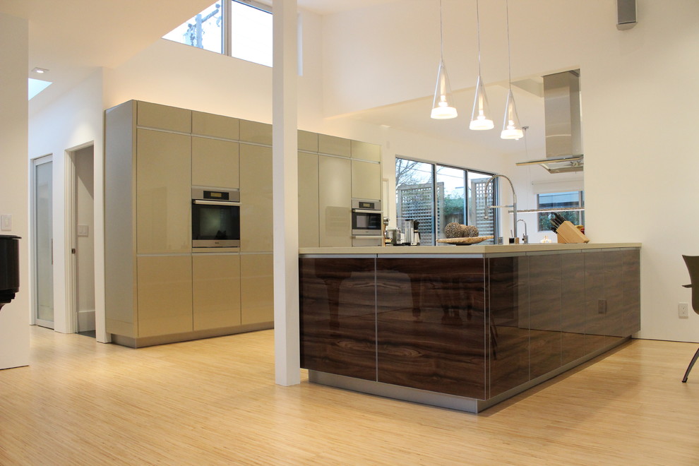 Foto di una cucina moderna di medie dimensioni con lavello sottopiano, ante lisce, parquet chiaro, ante grigie, top in superficie solida, elettrodomestici in acciaio inossidabile, penisola e pavimento marrone
