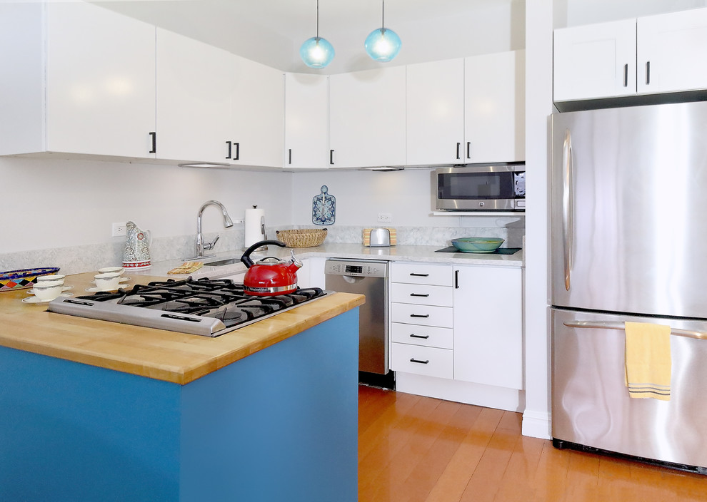 Inredning av ett 50 tals litet vit vitt kök, med en undermonterad diskho, släta luckor, vita skåp, bänkskiva i kvarts, vitt stänkskydd, stänkskydd i sten, rostfria vitvaror, mellanmörkt trägolv, en halv köksö och brunt golv