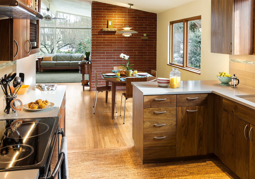 Bild på ett mellanstort retro kök, med en undermonterad diskho, släta luckor, skåp i mörkt trä, beige stänkskydd, stänkskydd i glaskakel, rostfria vitvaror, korkgolv och en halv köksö