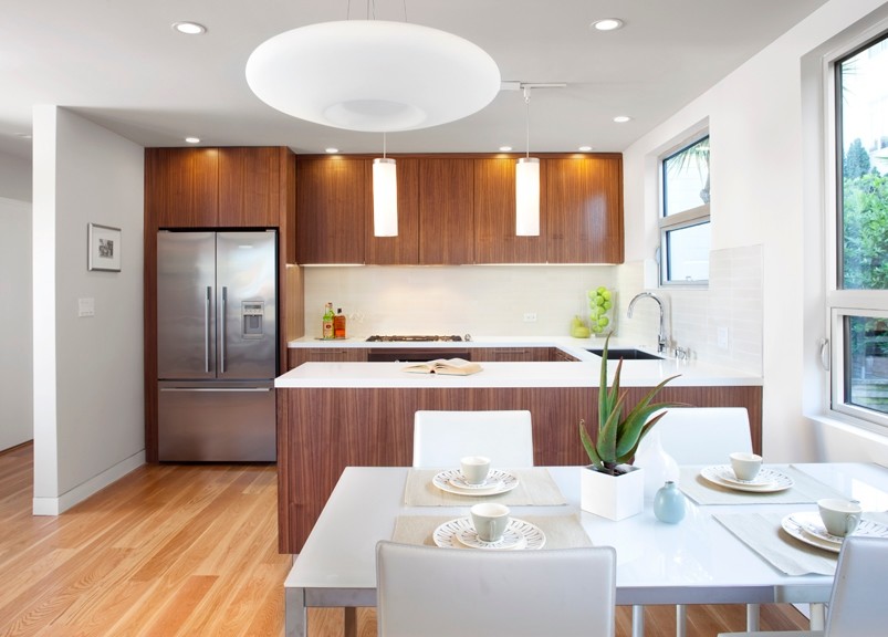 Inspiration for a small 1950s u-shaped light wood floor eat-in kitchen remodel in San Francisco with an undermount sink, flat-panel cabinets, medium tone wood cabinets, quartz countertops, white backsplash, ceramic backsplash, stainless steel appliances and no island