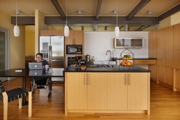 Large 1950s l-shaped medium tone wood floor kitchen photo in Seattle with a farmhouse sink, flat-panel cabinets, medium tone wood cabinets, soapstone countertops, stainless steel appliances and an island