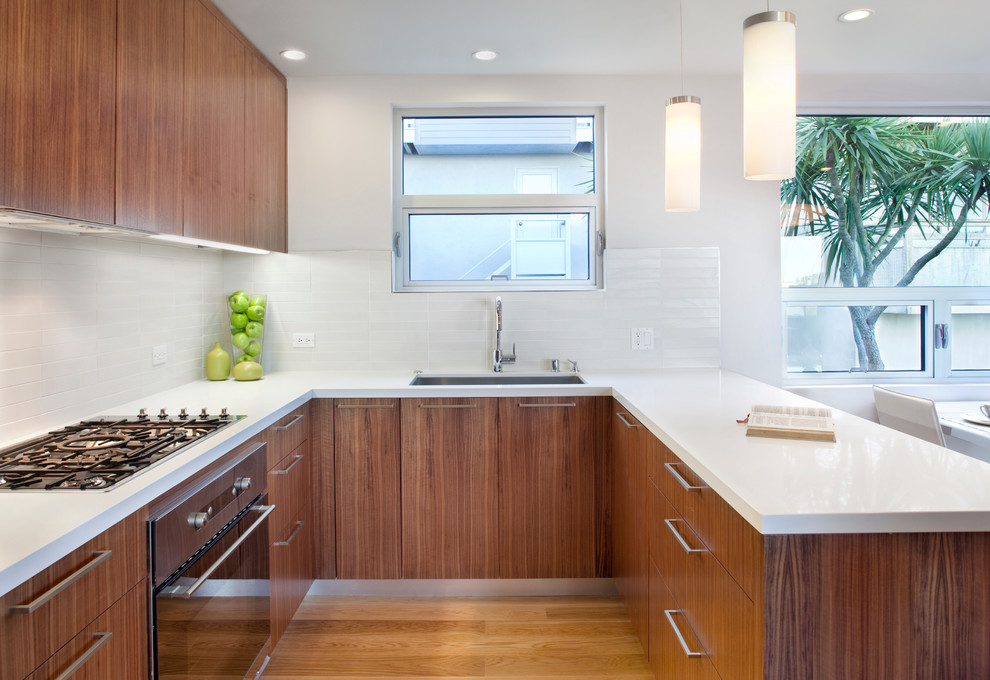 Cette photo montre une cuisine moderne avec un placard à porte plane et un électroménager en acier inoxydable.