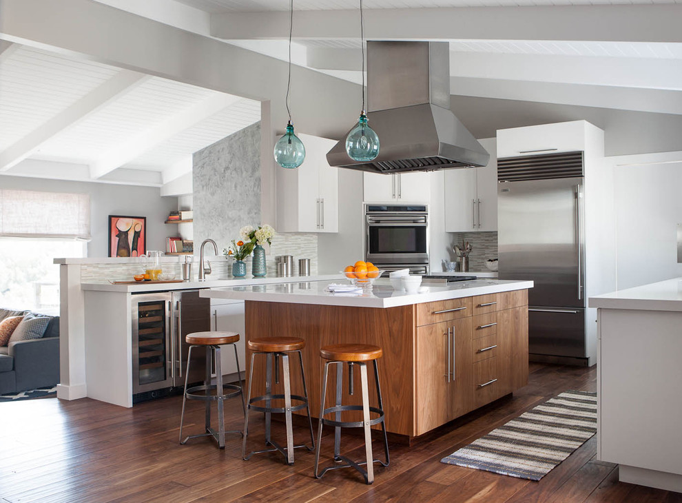 Example of a mid-sized trendy u-shaped medium tone wood floor eat-in kitchen design in San Francisco with stainless steel appliances, flat-panel cabinets, medium tone wood cabinets, quartz countertops, white backsplash, glass tile backsplash and an island