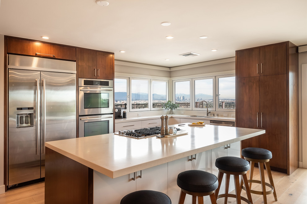 Example of a large trendy l-shaped medium tone wood floor kitchen design in Los Angeles with a drop-in sink, flat-panel cabinets, dark wood cabinets and stainless steel appliances
