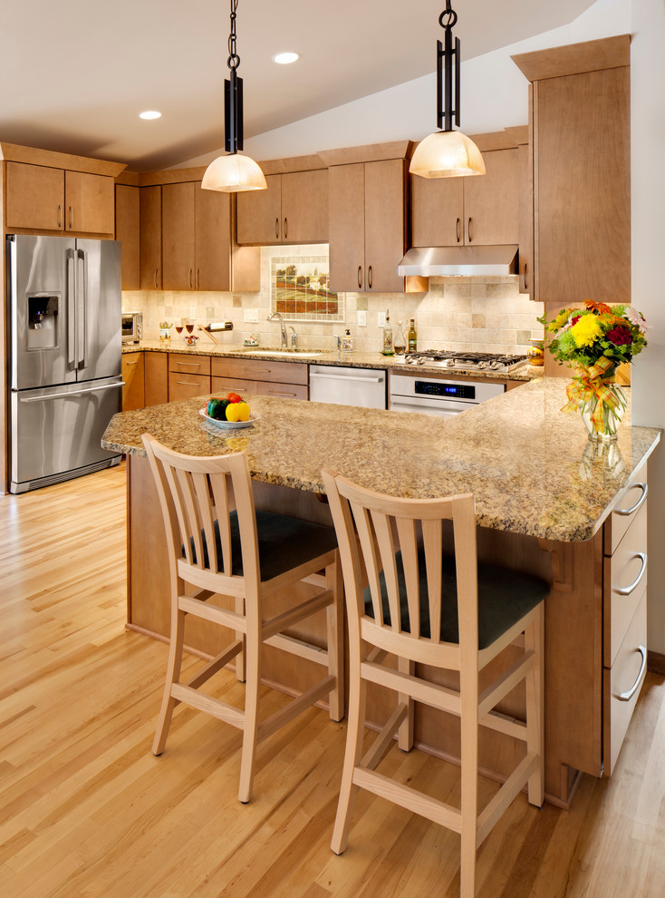 Foto på ett mellanstort 50 tals kök, med en undermonterad diskho, släta luckor, skåp i mellenmörkt trä, granitbänkskiva, vitt stänkskydd, stänkskydd i stenkakel, rostfria vitvaror, ljust trägolv och en halv köksö