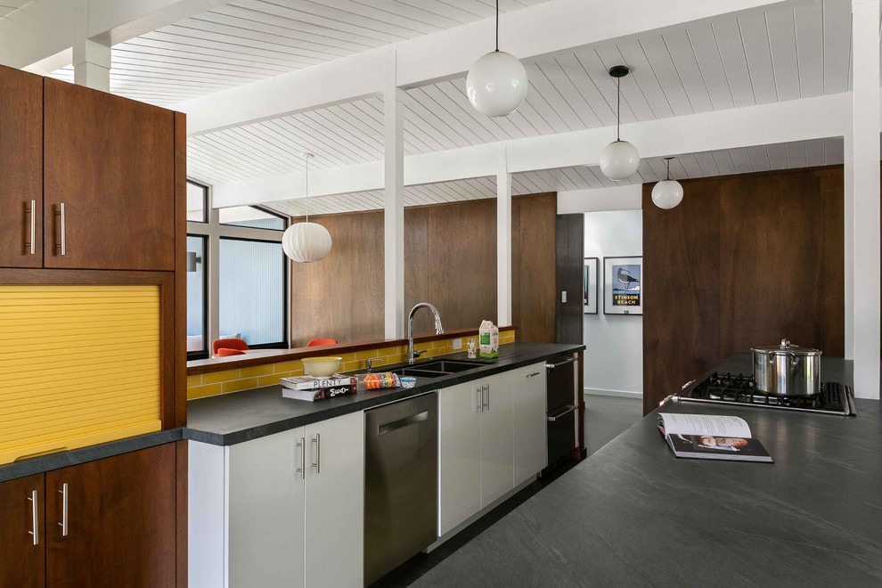 Photo of a retro kitchen in San Francisco with a double-bowl sink, flat-panel cabinets, white cabinets, yellow splashback, metro tiled splashback, stainless steel appliances and grey worktops.