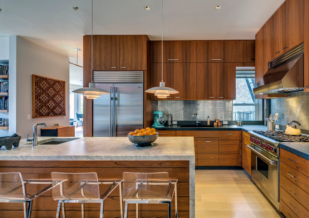 Bild på ett mellanstort retro kök, med en undermonterad diskho, släta luckor, skåp i mellenmörkt trä, stänkskydd med metallisk yta, rostfria vitvaror, ljust trägolv och en köksö