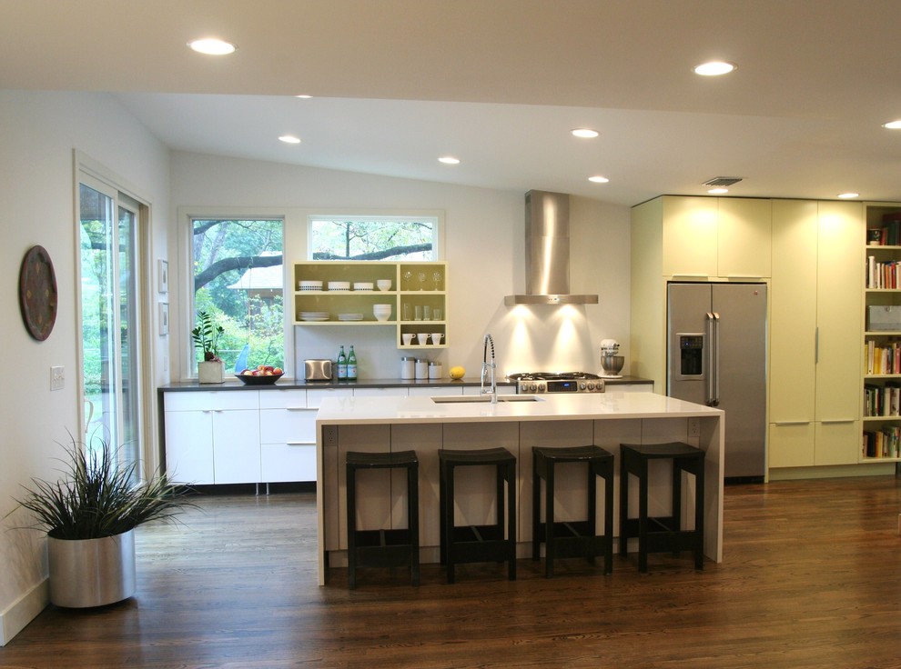 Exemple d'une cuisine parallèle rétro avec un électroménager en acier inoxydable, un évier encastré, un placard sans porte et des portes de placard jaunes.