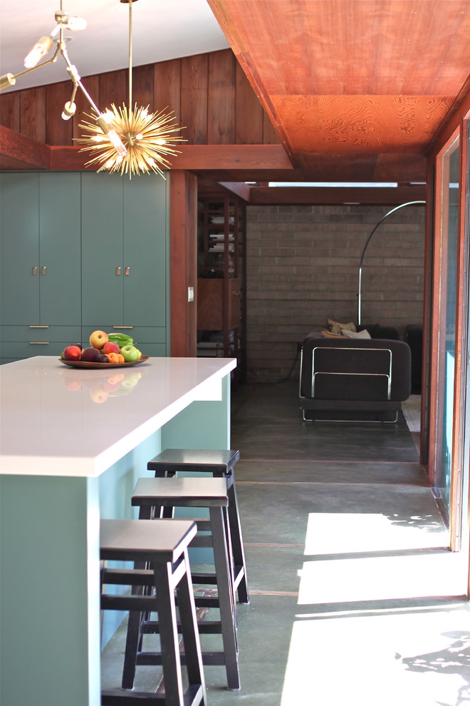 Bild på ett retro kök, med släta luckor, gröna skåp, bänkskiva i kvarts, integrerade vitvaror och betonggolv