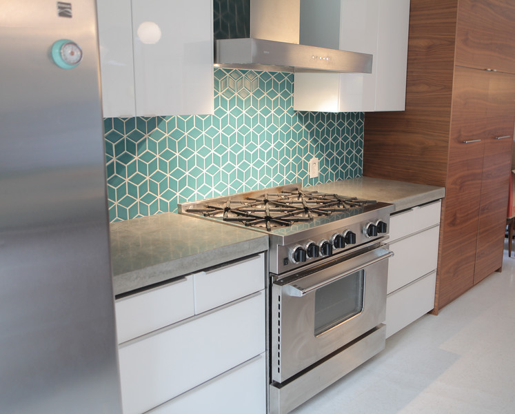 Photo of a medium sized retro galley kitchen/diner in San Francisco with a submerged sink, flat-panel cabinets, medium wood cabinets, concrete worktops, blue splashback, ceramic splashback, stainless steel appliances, lino flooring and an island.