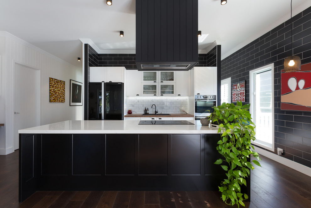 Bild på ett 50 tals kök, med skåp i shakerstil, grått stänkskydd, svarta vitvaror, mörkt trägolv, en köksö och brunt golv