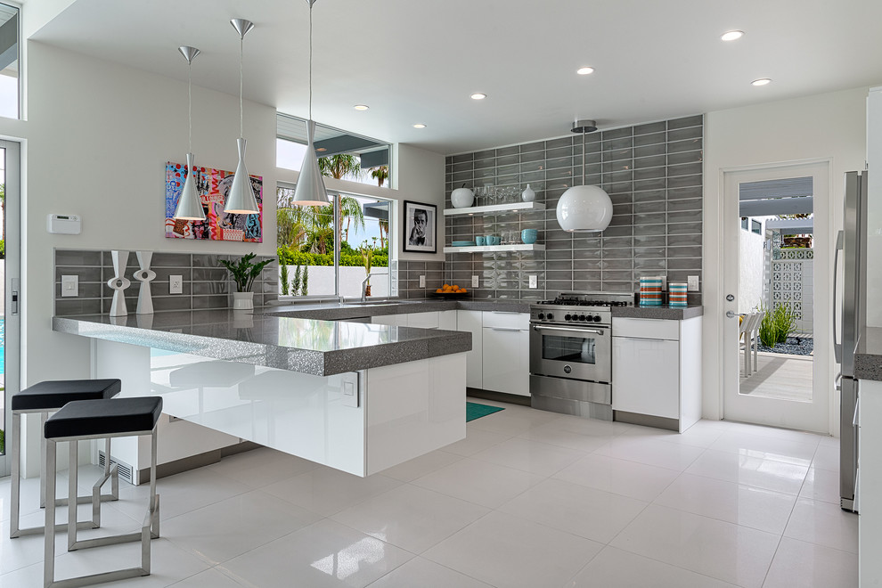 Immagine di una cucina ad U minimalista con ante lisce, ante bianche, paraspruzzi grigio, elettrodomestici in acciaio inossidabile e penisola