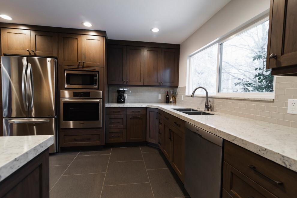 Photo of a medium sized retro l-shaped kitchen/diner in Salt Lake City with a double-bowl sink, shaker cabinets, dark wood cabinets, engineered stone countertops, grey splashback, ceramic splashback, stainless steel appliances, ceramic flooring, no island, grey floors and grey worktops.
