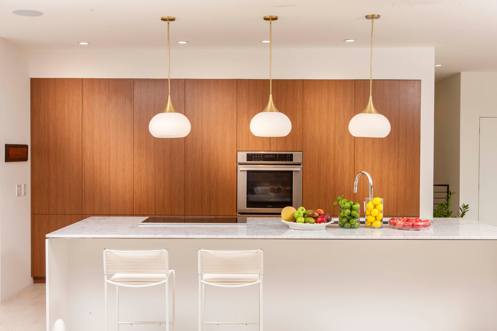Cette photo montre une cuisine rétro en bois brun avec un placard à porte plane, un électroménager en acier inoxydable, îlot et un plan de travail blanc.