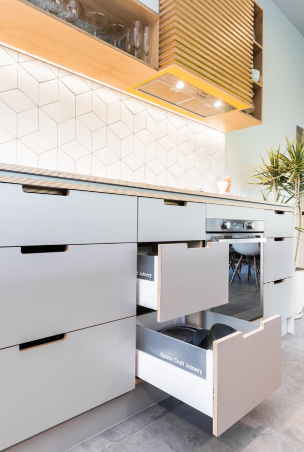This is an example of a large retro galley kitchen/diner in Adelaide with a submerged sink, flat-panel cabinets, grey cabinets, white splashback, ceramic splashback, stainless steel appliances, ceramic flooring and an island.