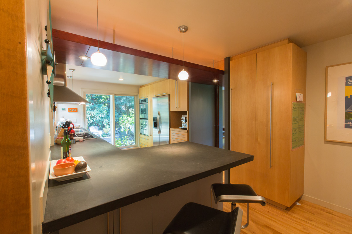 Стильный дизайн: угловая кухня в стиле ретро с обеденным столом, накладной мойкой, плоскими фасадами, светлыми деревянными фасадами, светлым паркетным полом и коричневым полом без острова - последний тренд