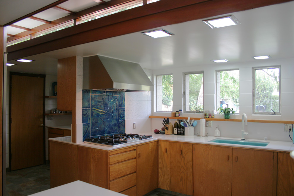 This is an example of a large retro l-shaped kitchen/diner in San Francisco with flat-panel cabinets, medium wood cabinets, engineered stone countertops, blue splashback, ceramic splashback and an island.