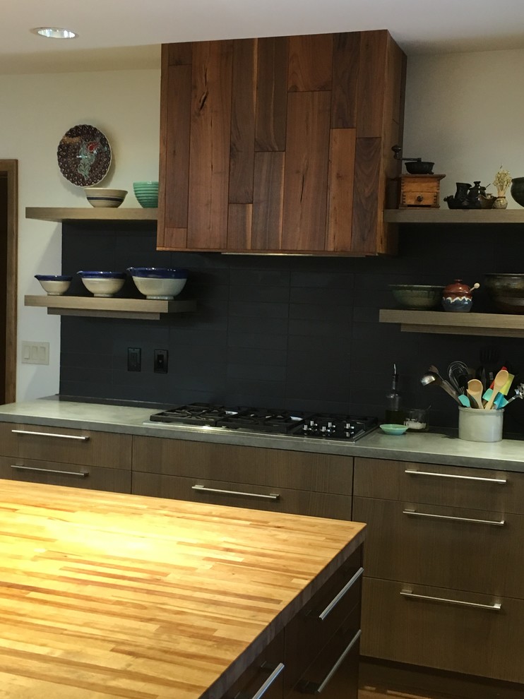 Foto di una cucina minimalista con ante lisce, ante grigie, top in cemento, paraspruzzi nero, paraspruzzi in gres porcellanato, elettrodomestici in acciaio inossidabile e pavimento in sughero