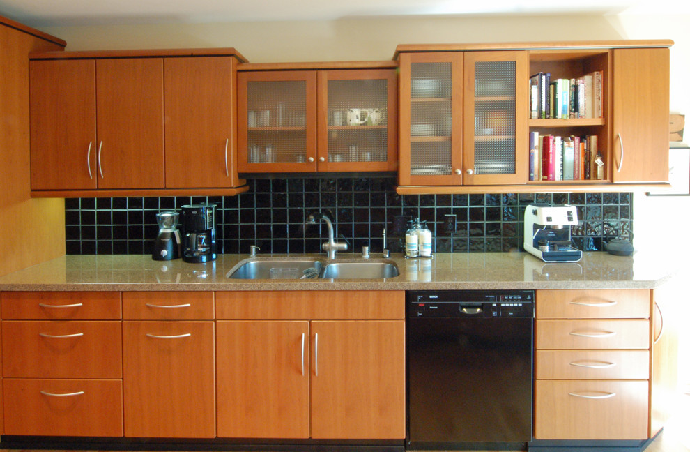 Inredning av ett modernt stort kök, med en undermonterad diskho, släta luckor, skåp i mellenmörkt trä, granitbänkskiva, svart stänkskydd, stänkskydd i keramik, svarta vitvaror, mellanmörkt trägolv och en köksö