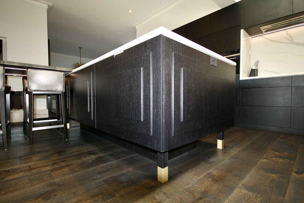 Foto på ett mycket stort funkis vit kök, med en nedsänkt diskho, luckor med upphöjd panel, svarta skåp, bänkskiva i kvarts, vitt stänkskydd, stänkskydd i sten, svarta vitvaror, mörkt trägolv, flera köksöar och svart golv