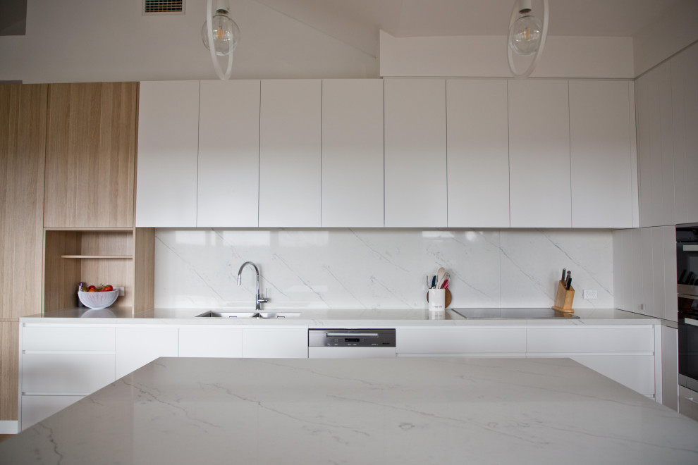 Inspiration for a medium sized contemporary open plan kitchen in Sydney with a double-bowl sink, white cabinets, quartz worktops, engineered quartz splashback, light hardwood flooring and an island.
