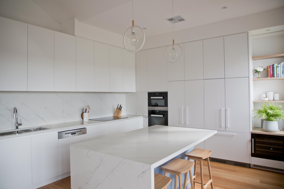Example of a mid-sized trendy light wood floor open concept kitchen design in Sydney with a double-bowl sink, white cabinets, quartzite countertops, quartz backsplash and an island