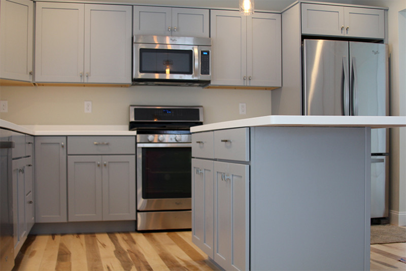 Foto på ett funkis kök, med en undermonterad diskho, skåp i shakerstil, grå skåp, bänkskiva i koppar, vitt stänkskydd, rostfria vitvaror, ljust trägolv och en köksö