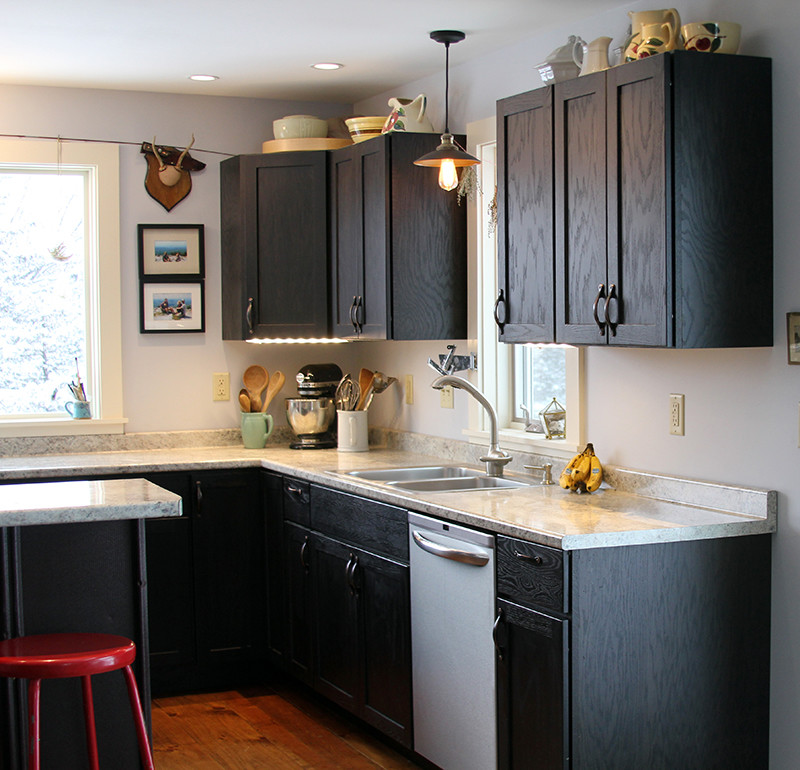 Photo of a small modern u-shaped kitchen/diner in Burlington with a double-bowl sink, shaker cabinets, black cabinets, laminate countertops, grey splashback, stainless steel appliances, light hardwood flooring and a breakfast bar.