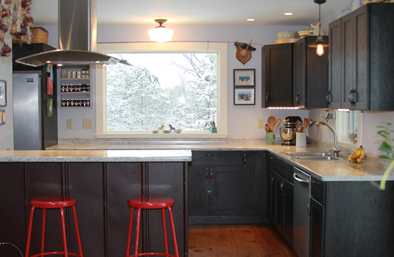 Exempel på ett litet modernt kök, med en dubbel diskho, skåp i shakerstil, svarta skåp, laminatbänkskiva, grått stänkskydd, rostfria vitvaror, ljust trägolv och en halv köksö