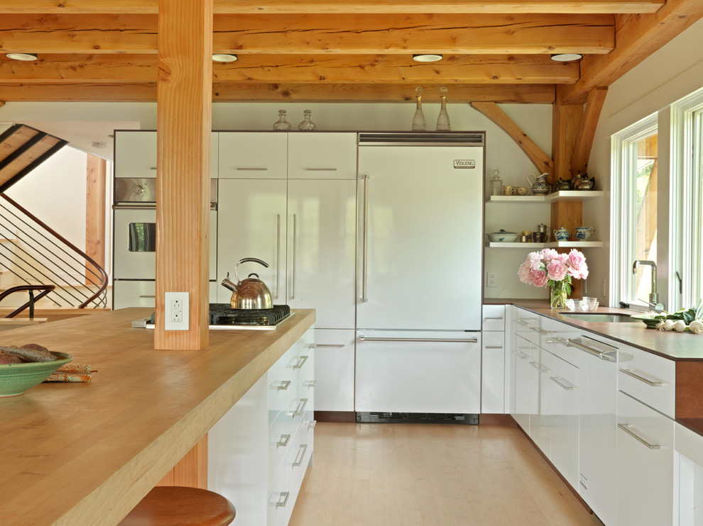 Источник вдохновения для домашнего уюта: кухня в современном стиле с плоскими фасадами, белыми фасадами, деревянной столешницей и техникой под мебельный фасад