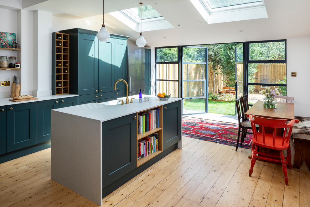 Mittelgroße Klassische Wohnküche mit Schrankfronten im Shaker-Stil, grünen Schränken, hellem Holzboden, Kücheninsel, weißer Arbeitsplatte, Landhausspüle und beigem Boden in London
